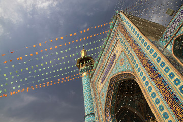 kolorowe flagi zdobiące fasadę zabytkowego meczetu w iranie podczas święta