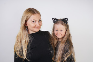 cute kind caucasian blonde mom and daughter posing on white background. a parent and a child experience love and hug.