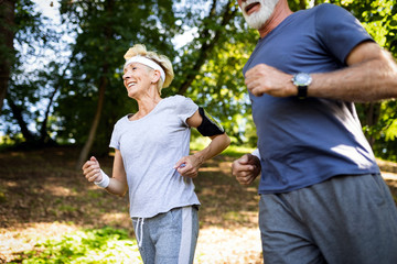 Naklejka na ściany i meble Senior couple jogging and running outdoors in nature