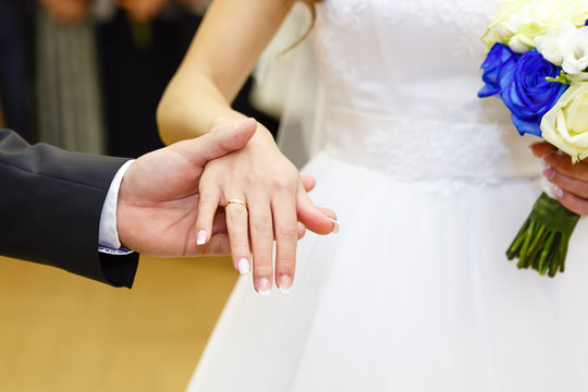 Close Up of groom holding hand of bride with gold diamond wedding ring. People, holidays, engagement and love concept