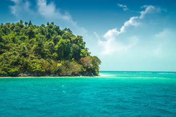 Beautiful paradise green island in the ocean. Tropics. Thailand Andaman Sea. Seascape with azure water and an island with many plants.