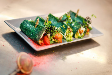 The girl's chef is preparing green crepe roles with basil cheese and stuffed. Green cheese. Cooking in the kitchen