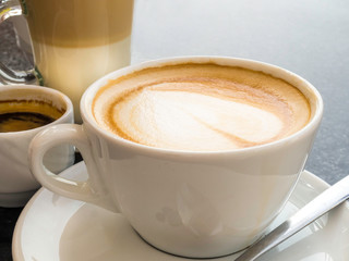 Hot cappuccino, espresso coffee in the white cups, latte on the table