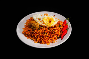 Spicy Noodle with meatball and fried egg isolated on black background