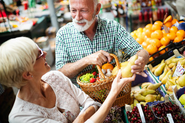 Smiling senior couple buying vegetables and at the merket