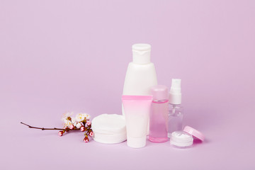 Face and body care products with spring bloom (tonic or lotion, serum, cream, shampoo, micellar water, cotton pads and sticks, shaver) on purple. Freshness and body care. Skin cosmetics. Border banner