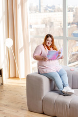 Obraz premium Positive plum woman reading about modern fashion trends