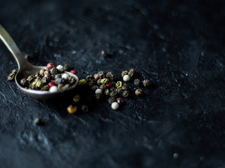 Spoon with allspice on a dark stone background