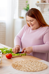 Joyful nice woman preparing salad with lettuce