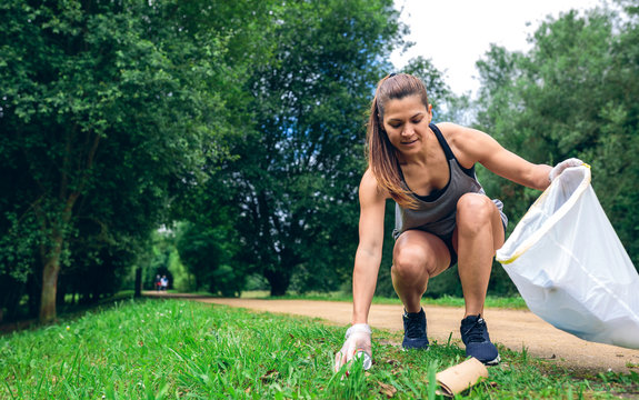 Girl crouching with garbage bag doing plogging