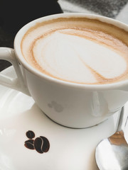 Cup of cappuccino on the table, coffee shop background.