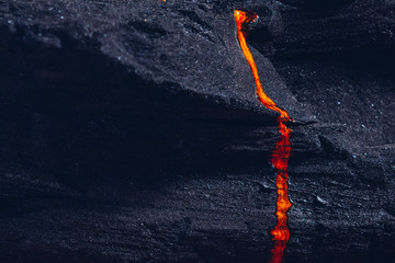 Closeup of orange pearl paint on a black textured stone