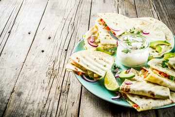 Mexican traditional food, quesadilla with chicken and vegetables, with white sauce, rustic wooden background copy space
