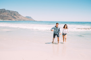 Fototapeta na wymiar Junges Paar voller Liebe, Freude und Freiheit am Strand im sonnigen Kapstadt
