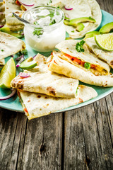 Mexican traditional food, quesadilla with chicken and vegetables, with white sauce, rustic wooden background copy space