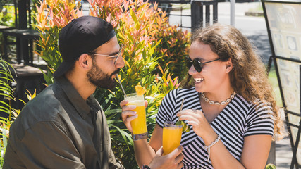 Beautiful woman giving her boyfriend drink while happily laughing – Young couple having fun on a date – Relationship lovers concept on a bright day – Image