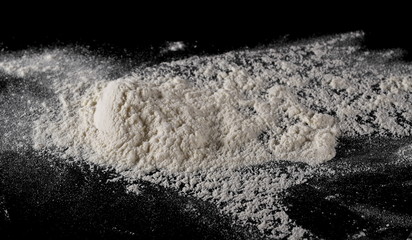 Fototapeta na wymiar Wheat flour pile isolated on black background, powder texture