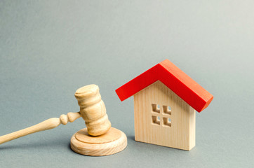 Miniature wooden house and judge's hammer. The concept of resolving property disputes. Property alienation. Confiscated housing. Nationalization. Services of a lawyer. Court. Gavel. Law