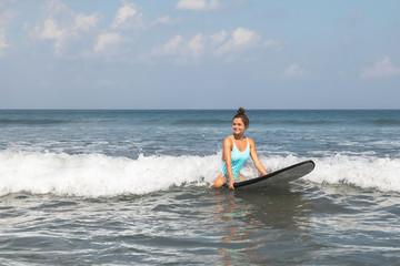 Young woman surfer is trying to catch the wave