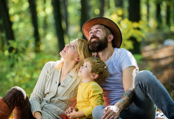 Fototapeta premium Happy son with parents relax in autumn forest. Mother, cowboy father love their little boy child. Spring mood. Happy family day. Sunny weather. Healthy food. Family picnic. Spring everywher
