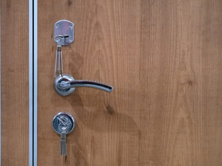closeup of entrance wooden door with few locks with keys and chrome handle