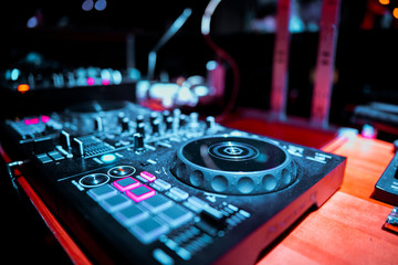 Fototapeta na wymiar Night club, nightlife concept. DJ hands hold microphone and mixing DJ remote. Neon light