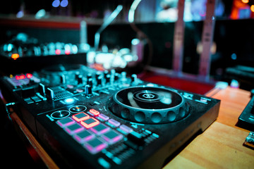 Night club, nightlife concept. DJ hands hold microphone and mixing DJ remote. Neon light