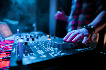 Night club, nightlife concept. DJ hands hold microphone and mixing DJ remote. Neon light