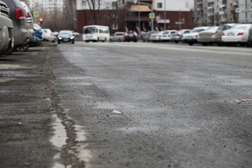 Broken city asphalt road with a lot of pits. Depressive urban landscape.
