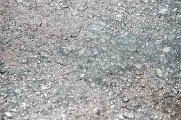 Shards of broken car glass on the asphalt road