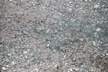 Shards of broken car glass on the asphalt road