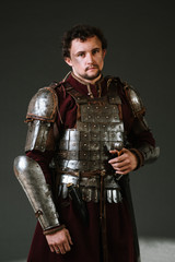 Medieval man knight in armor and weapon on dark background. Portrait of the knight