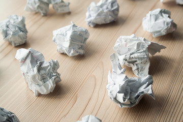 Many crumpled white paper balls on wooden table. Texture of crumpled paper balls.  Crumpled paper as brainstorming, creativity concept, mistakes and creation symbol.