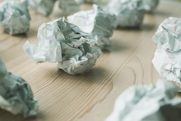 Many crumpled white paper balls on wooden table. Texture of crumpled paper balls.  Crumpled paper as brainstorming, creativity concept, mistakes and creation symbol.