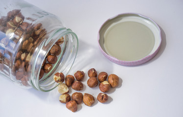 Raw hazelnuts scattered from glass jar isolated on white background. Fresh organic brown nuts in studio interior. Many lots of pieces of beer nuts texture pattern. Common farm crop of Black Sea Region