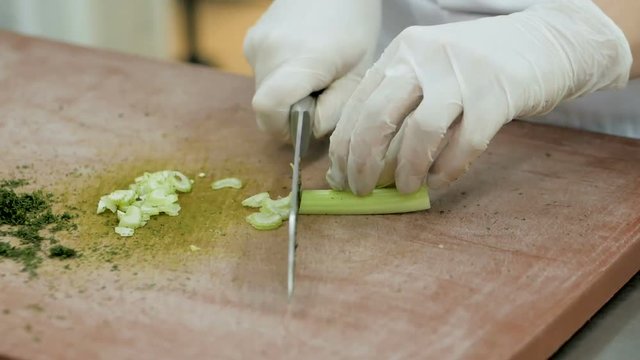Close up of chef slicing fresh celery sticks on a wooden chopping board