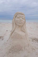 beach artist has modeling an artistic woman bust out of sand at a white beach a summer vacation scene