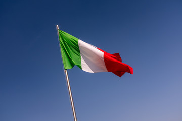 Close up of the Italian flag flying in the blue sky