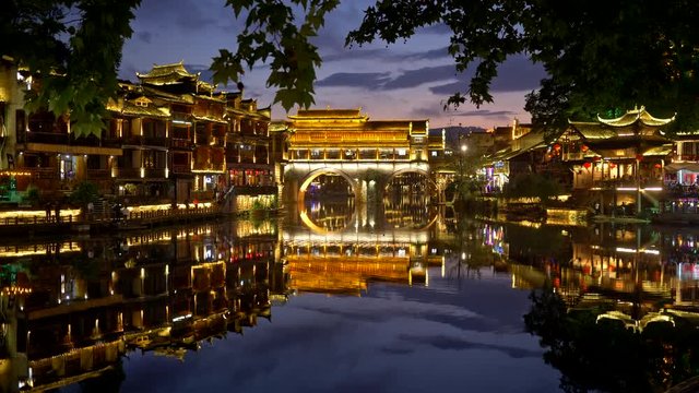 Fenghuang County, China. Night view of lights of Fenghuang Ancient Town. Beautiful colorful lights' reflections are seen in the Tuojiang River. 'Fenghuang' means 'Phoenix' in Chinese. 4K
