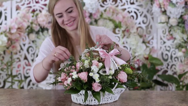 Woman Florist Preparing Beautiful Flower Bouquet of roses in white basket.