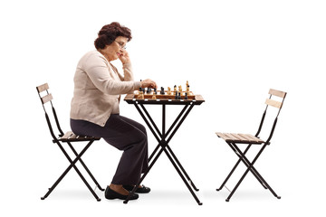 Senior woman with a chessboard at a table looking at the chess figure