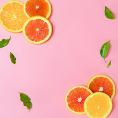 Square picture top view six pieces of slice orange and small leaves on pink background