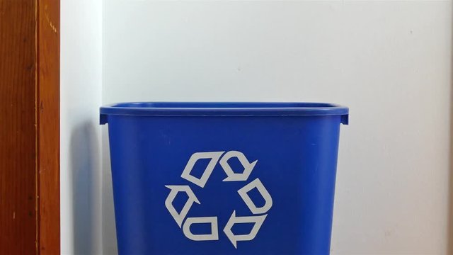Hand is adding empty plastic bottles to recycling bin