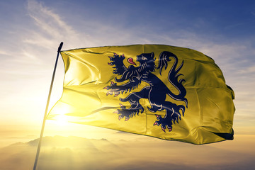 Flanders region of Belgium flag waving on the top sunrise mist fog