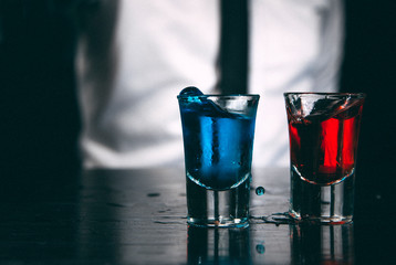Blue and red alcohol shots on a black counter.