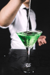 Green martini cocktail with fruit, black background. 
