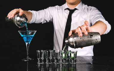 Barman being multipractic, makes two cocktails at once.