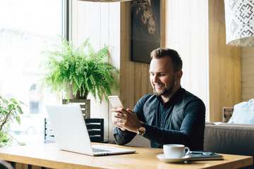 Fototapeta premium Stylish young man calling by the phone to solve business problems. Online consultation by phone. Freelancer discussing the development and planning of his online project. Outsourcing. Mobile services.