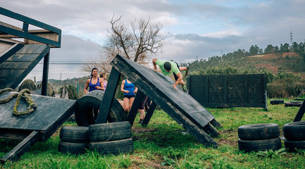 Group of participants in an obstacle course climbing an inverted wall
