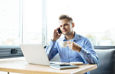 Stylish young man calling by the phone to solve business problems. Online consultation by phone. Freelancer discussing the development and planning of his online project. Outsourcing. Mobile services.